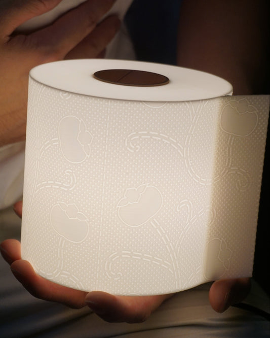 Close-up of a hand gently holding the illuminated toilet paper lamp, clearly showing scale and detail