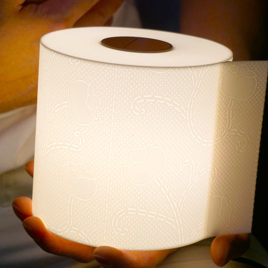Close-up of a hand gently holding the illuminated toilet paper lamp, clearly showing scale and detail