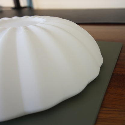Close-up of the Kueh Tutu lamp's beautifully curved shade on a desk, highlighting the smooth minimalist design and sculptural form
