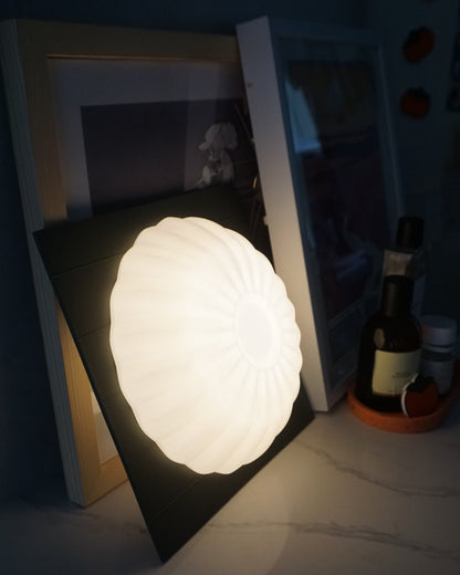 Kueh Tutu lamp leaning at an angle, showcasing its warm light glowing from both the front and the rear