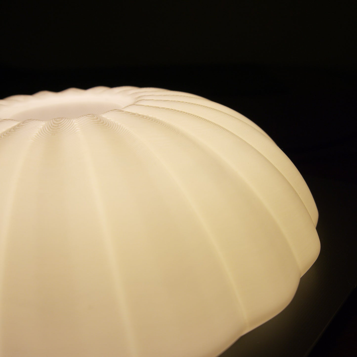 Close-up of the illuminated Kueh Tutu lamp, highlighting the warm glow diffusing through its beautifully curved shade