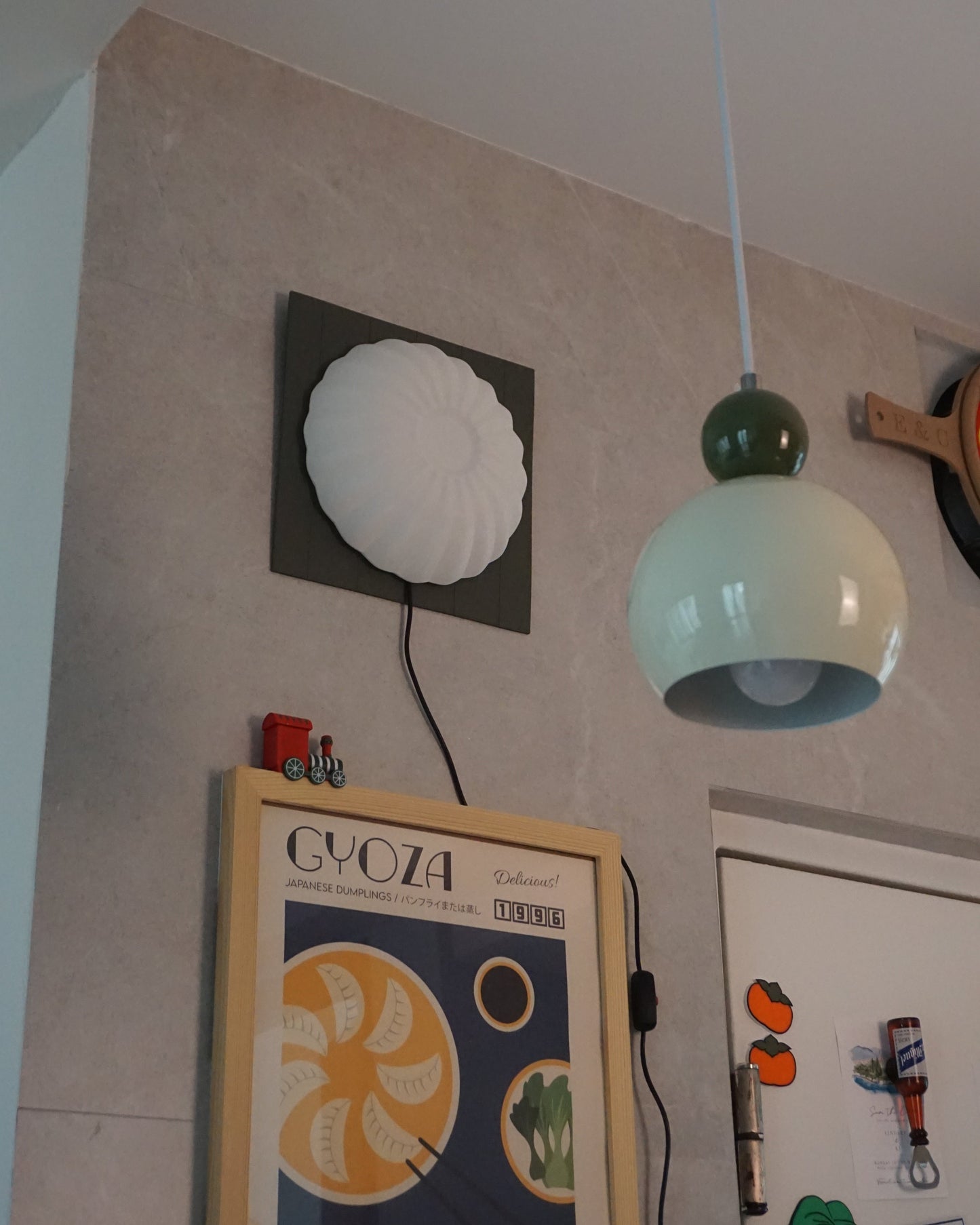 Kueh Tutu lamp, unlit, mounted on the wall alongside framed photos and other decorative elements