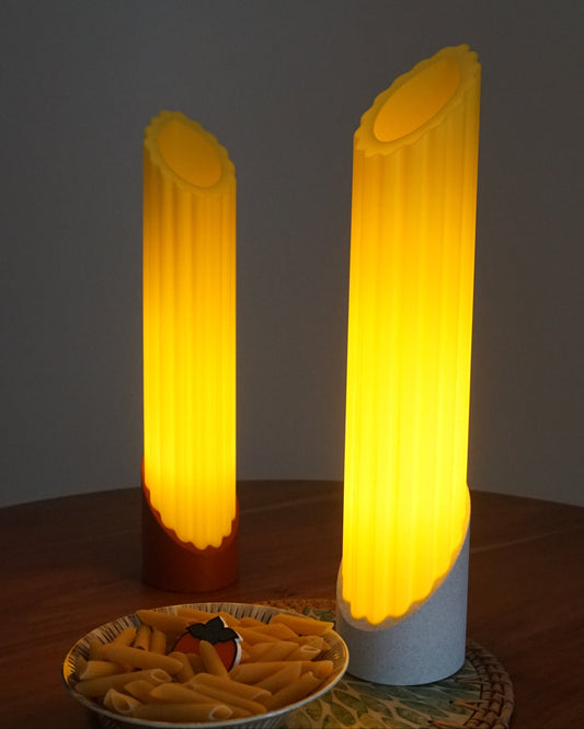Two Penne pasta lamps glowing warmly, styled alongside a bowl of pasta, on top a mini persimmon logo