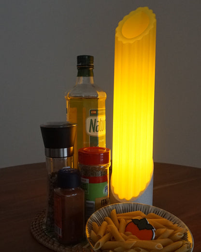 Single Penne pasta lamp standing next to seasoning and a bowl of raw pasta, on top a mini persimmon logo