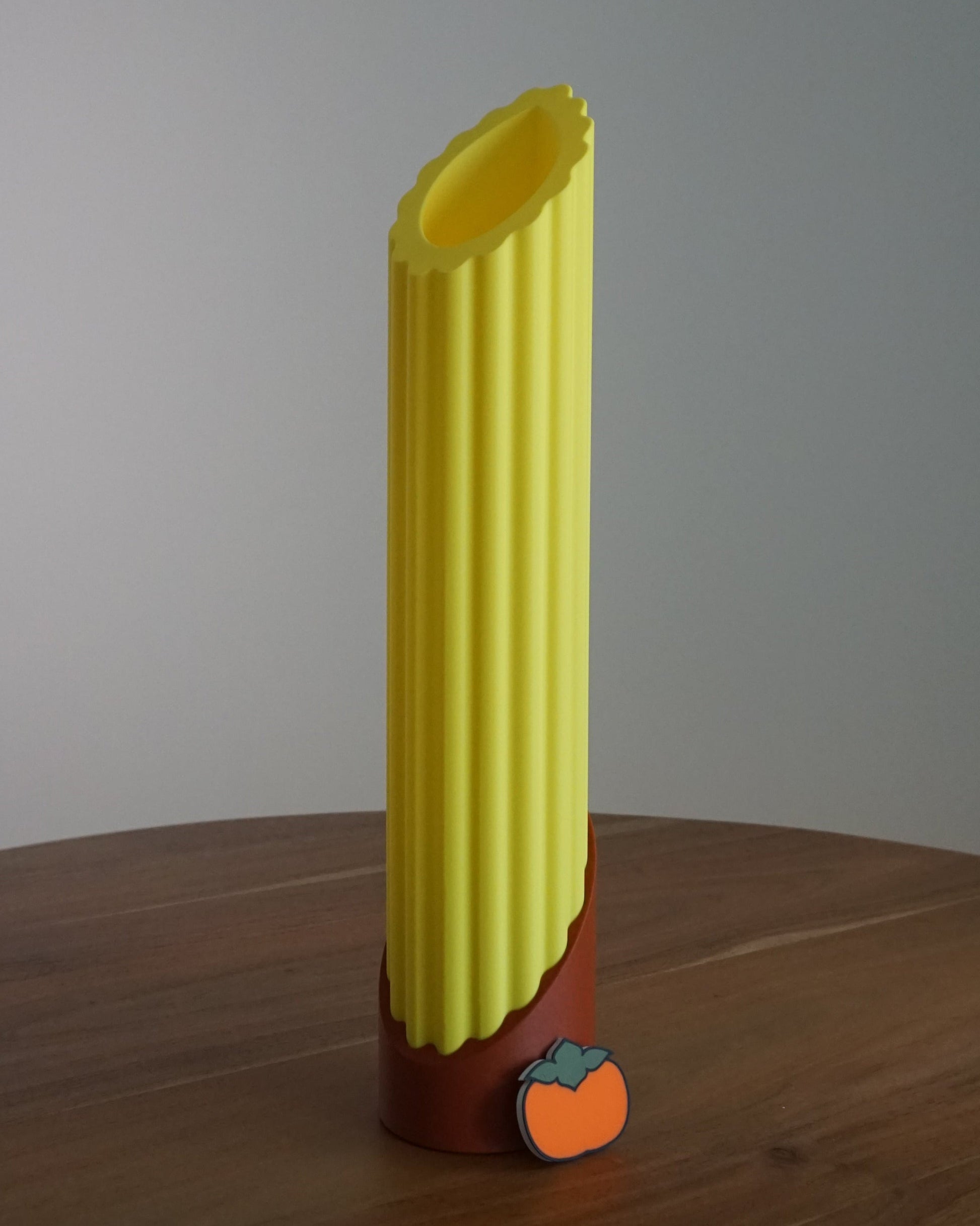 Single Penne pasta lamp featuring a tomato red base, unlit in bright daylight and a mini persimmon logo