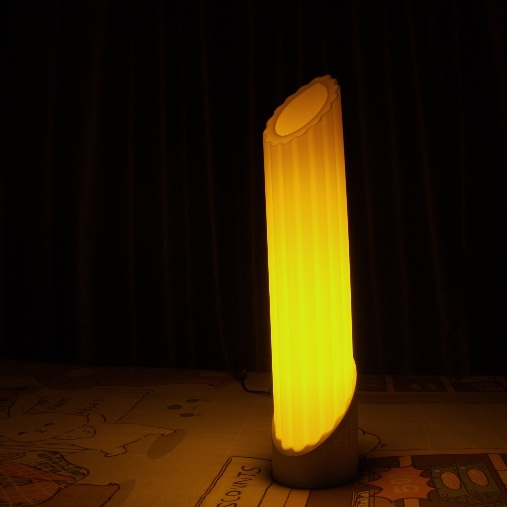 Illuminated penne pasta lamp glowing in complete darkness while resting on a bed, highlighting its soft ambient light